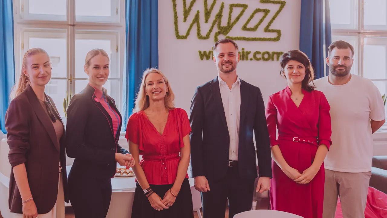 Tím Wizz Air pred stenou s logom