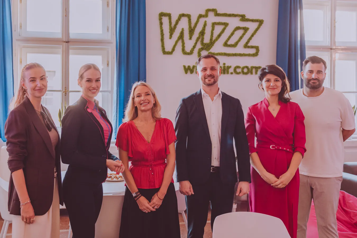 Tím Wizz Air pred stenou s logom